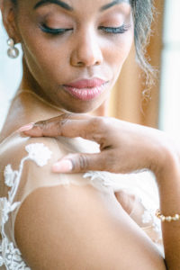 Gorgeous makeup on the black bride turn over looking her shoulder with hand on shoulder wearing Primrose from Lovely Bride boutique gown in Seattle Washington