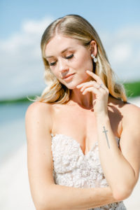 Luxury bride wear minimalist makeup bridal portrait with left hand caresses her left cheek looking down in pensive mode. Taking at Nizuc resort and Spa in Cancun. Dress by dress designer Galia Lahav. 