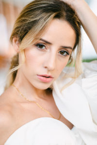Natural, elegant, timeless makeup for this elegant and luxury bride wearing wedding gown by Alon Livne White. She looks into the camera with hand pose on her head. 