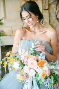 Beautiful Bride wearing blue tulle and she is playing with a beautiful flowers bouquet inside Sunstone Winery in Santa Ynez, CA